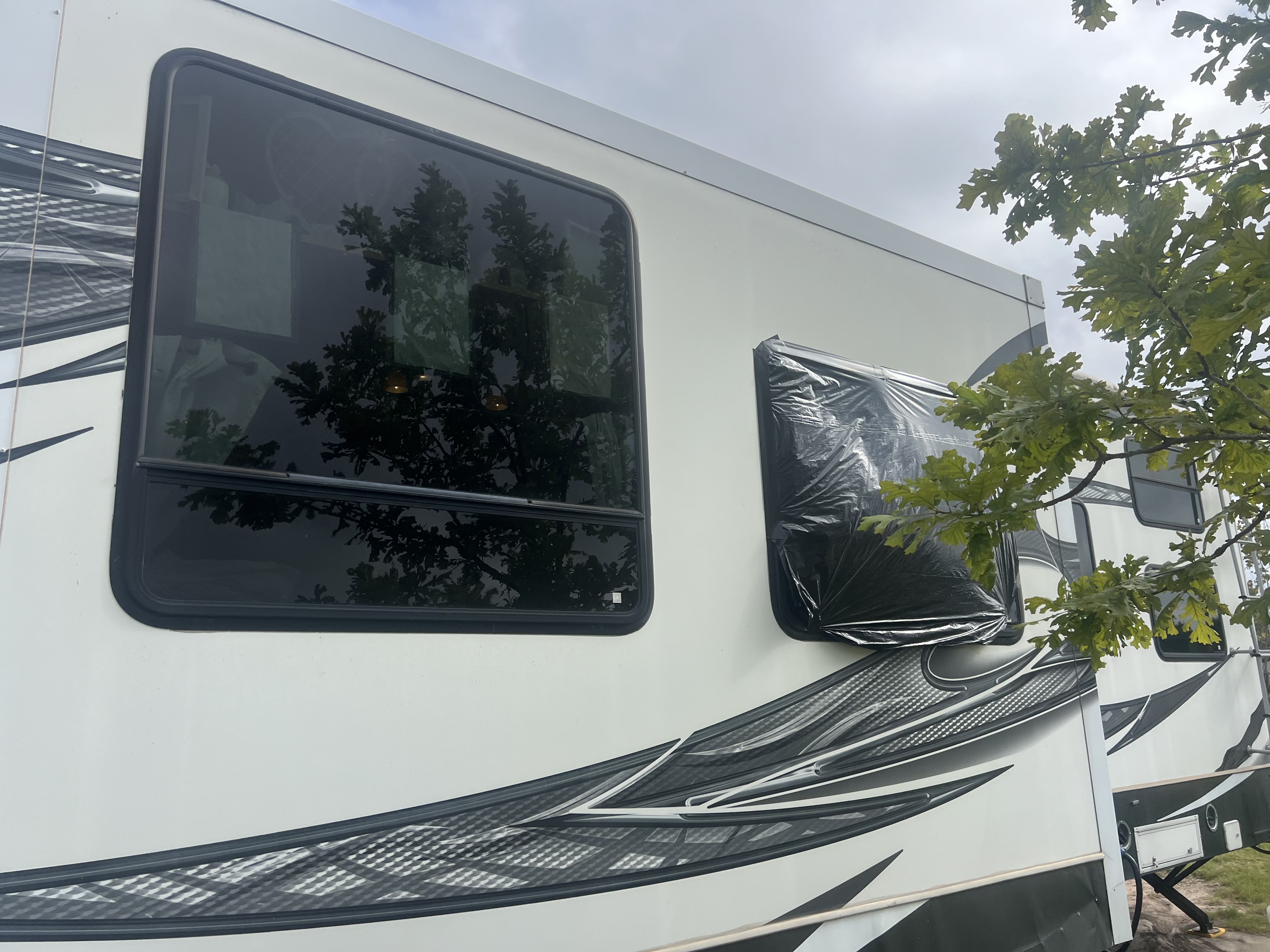 RV window with emergency weather protection installed — temporary cover applied over the damaged window opening to prevent water intrusion while the replacement window is sourced — Boss Bull Mobile RV Services