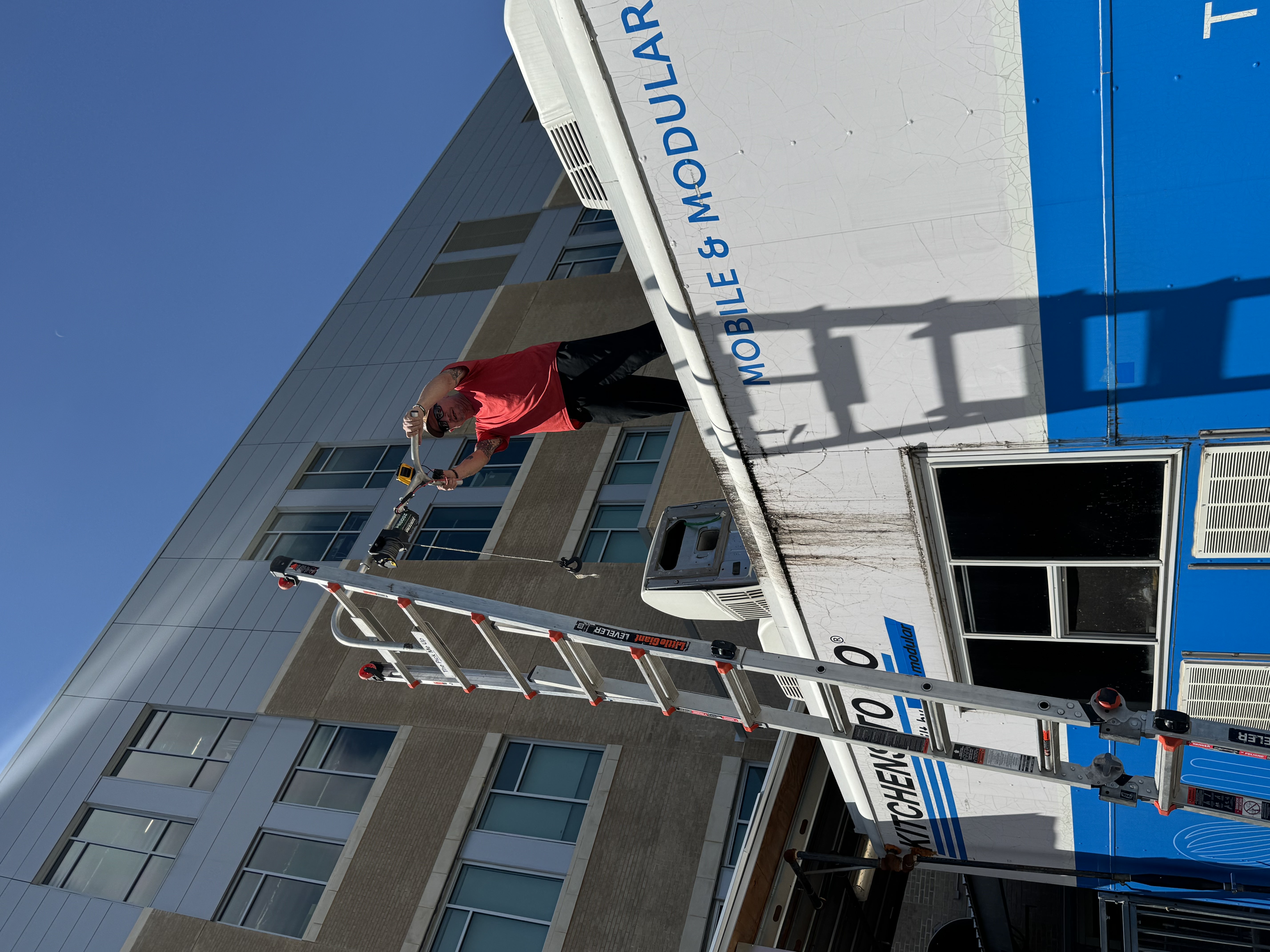 Boss Bull technician using a hoist system for on-site RV air conditioner installation at an Austin-area location — AC replacement performed in place without towing