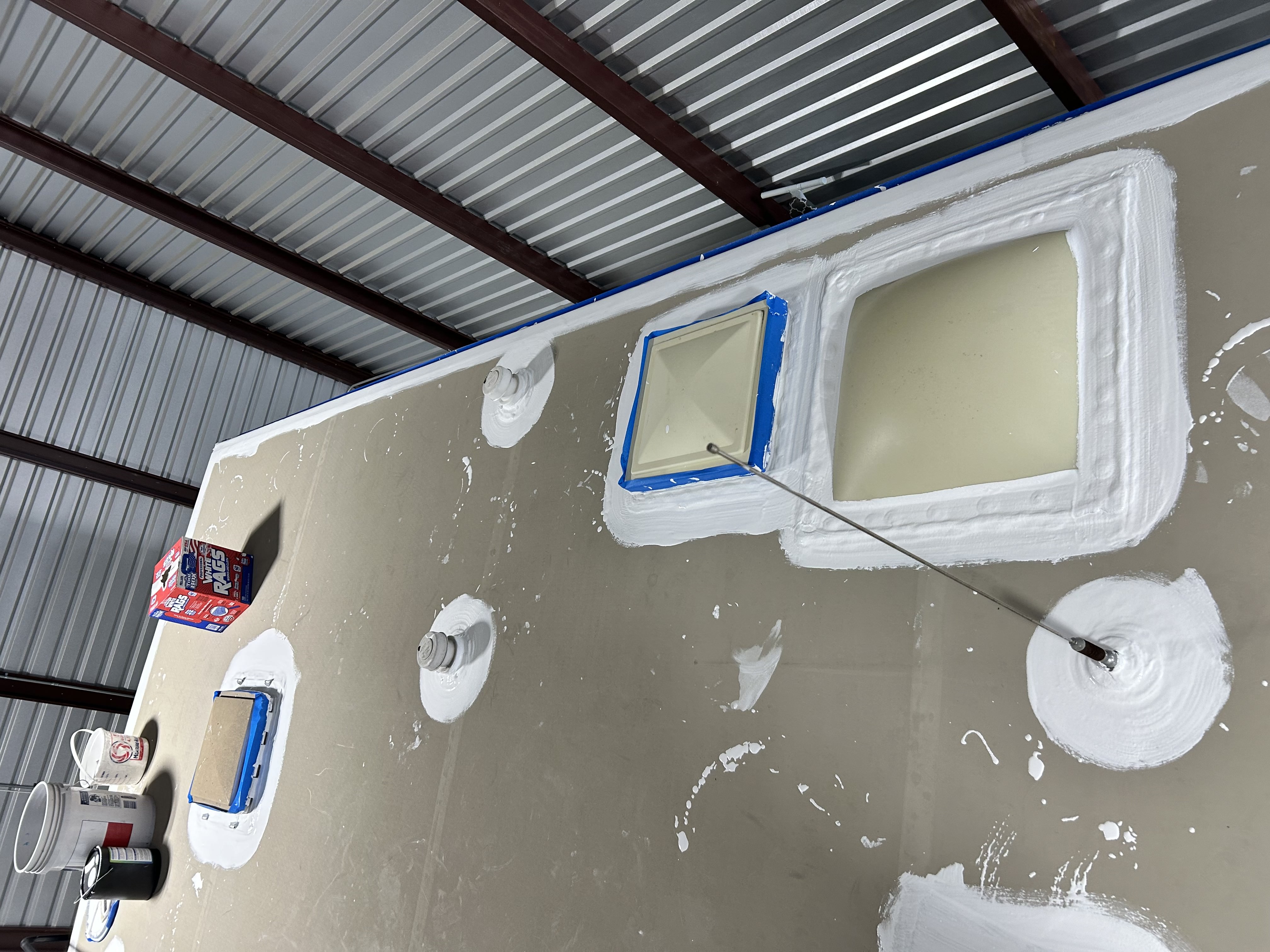 White lap sealant applied around an RV roof penetration flange during a preventive maintenance visit — freshly sealed vent base with surrounding membrane visible — Boss Bull Mobile RV Services
